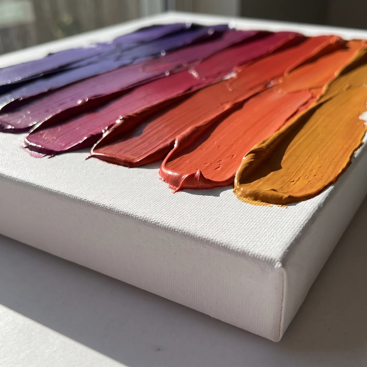 Kante der 3D-Leinwand von der Seite — weiße Seite mit 4 cm Tiefe und Bahnen dicker Acrylfarbe mit dem Spachtel aufgetragen, jede in einer anderen Farbe, zusammen ein Verlauf von Violett bis Bernstein