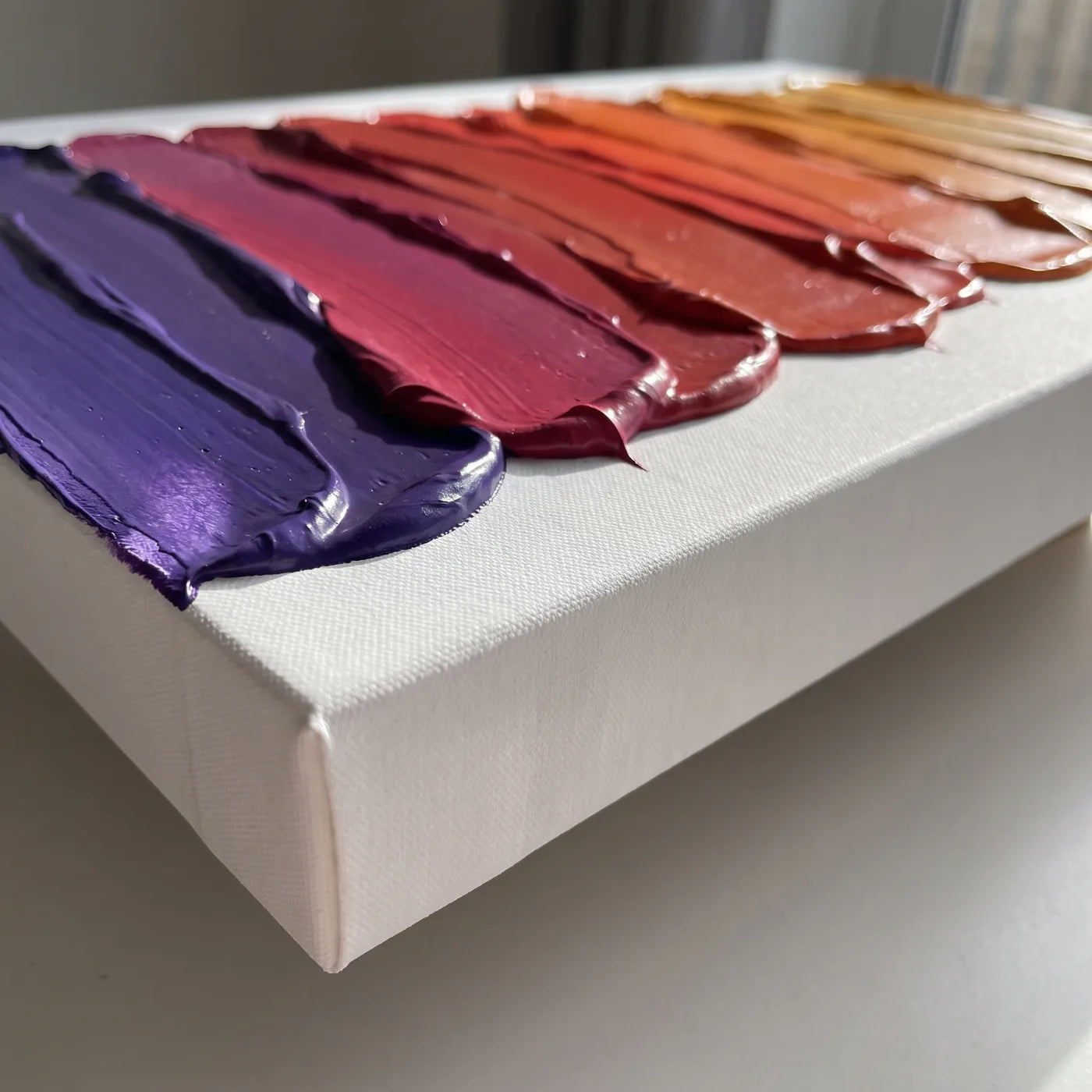 Kante der 3D+-Leinwand von der Seite — weiße Seite mit 5,8 cm Tiefe und Bahnen dicker Acrylfarbe mit dem Spachtel aufgetragen, jede in einer anderen Farbe, zusammen ein Verlauf von Violett bis Bernstein